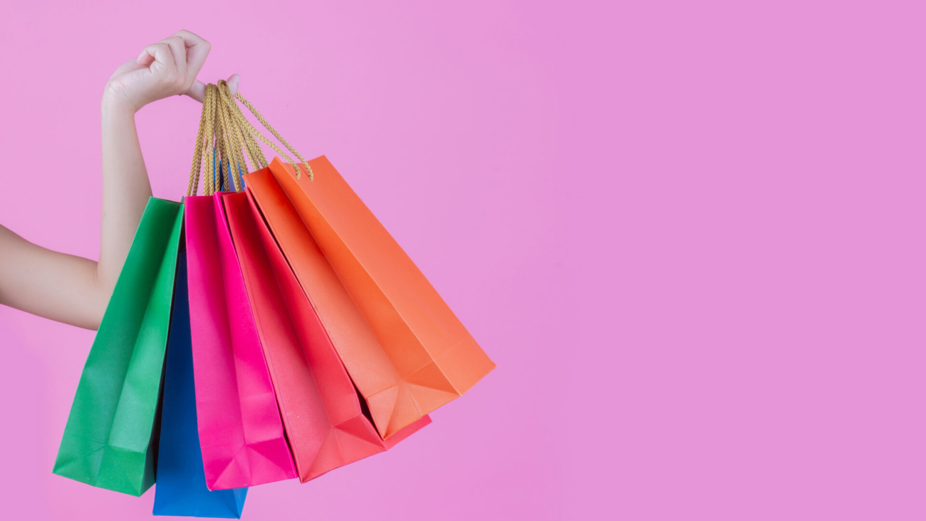 The girl holds a fashion shopping bag and beauty on a pink background.
