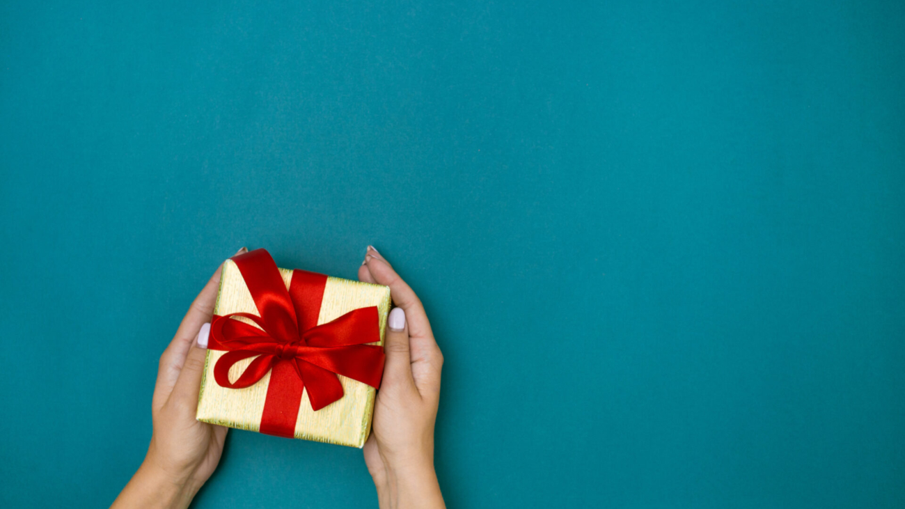 The female hands holding gift on blue background